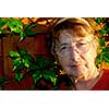 Portrait of an elderly woman outside with green vines