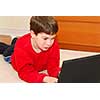 Little boy lying on the floor with portable computer