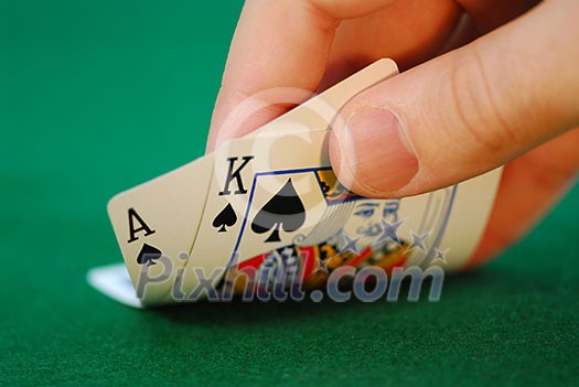 Man's hand lifting up playing cards at a poker table Man's hand lifting up playing cards at a poker table