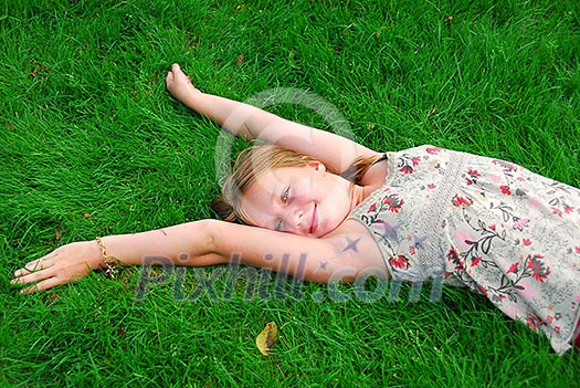 Young girl lying on green grass in the summer