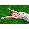 Young girl lying on green grass in the summer