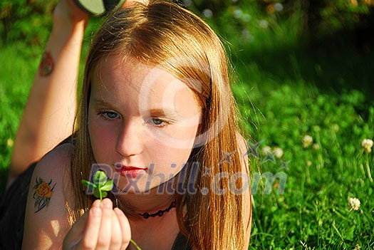 Young girl lying on green grass outside holding a green plant Young girl lying on green grass outside holding a green plant