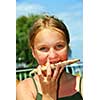 Young girl eating a slice of cheese pizza outside