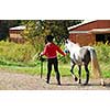 Young girl leading a white pony to stable