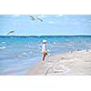 Young girl on a beach among flying seagulls