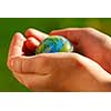 Child's hands holding a globe on green background