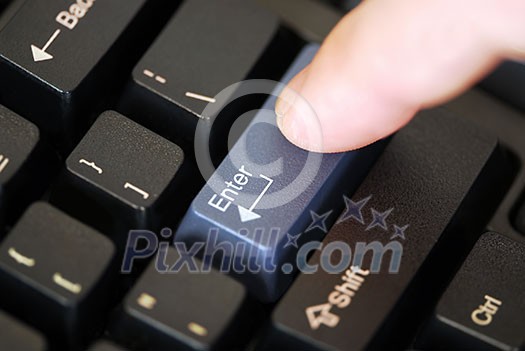 Macro of computer keyboard with finger pressing 'enter' key Macro of computer keyboard with finger pressing 'enter' key