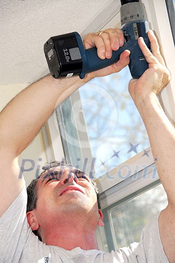 Man drilling a hole in a ceiling Man drilling a hole in a ceiling
