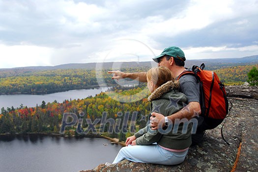Parent and child sitting on cliff edge enjoying scenic view Parent and child sitting on cliff edge enjoying scenic view