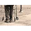 Senior man taking a walk in a park with the aid of a walking frame