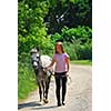 Young girl walking with a pony on a farm road