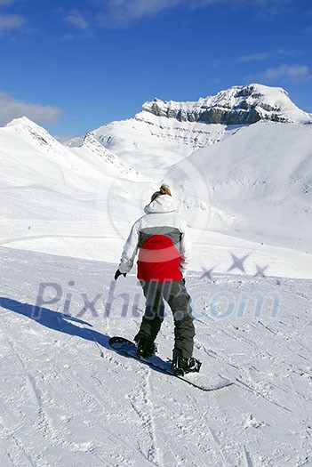 Girl snowboarding on the backdrop of scenic view in Canadian Rocky mountains ski resort Girl snowboarding on the backdrop of scenic view in Canadian Rocky mountains ski resort