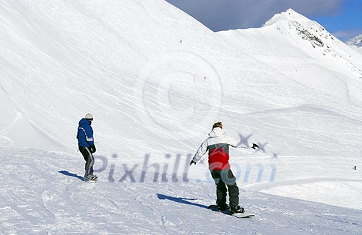 Couple snowboarding on the backdrop of scenic view in Canadian Rocky mountains ski resort Couple snowboarding on the backdrop of scenic view in Canadian Rocky mountains ski resort