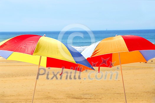 Two beach ubrella standing on ocean shore Two beach ubrella standing on ocean shore