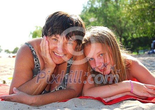 Portrait of grandmother and granddaughter lying on a sandy beach Portrait of grandmother and granddaughter lying on a sandy beach