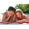 Portrait of grandmother and granddaughter lying on a sandy beach