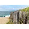 Ocean with sandy beach and wooden fence