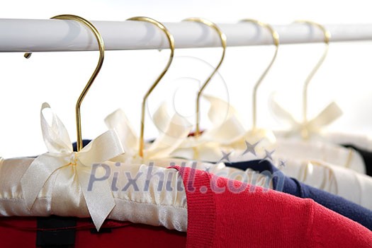 Colorful women's sweaters on a rack on padded hangers Colorful women's sweaters on a rack on padded hangers