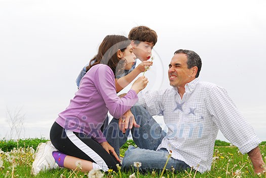 Children playing with their father blowing dandelions Children playing with their father blowing dandelions