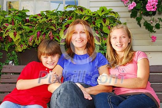 Portrait of a smiling family - mother and children - in front of the house Portrait of a smiling family - mother and children - in front of the house