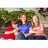 Portrait of a smiling family - mother and children - in front of the house