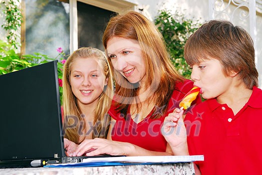 Mature woman working on computer at home with her children Mature woman working on computer at home with her children
