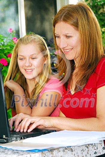 Mother and daughter working on computer at home in the backyard Mother and daughter working on computer at home in the backyard