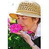 Portrait of a happy senior woman in her garden smelling flowers
