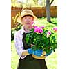 Senior woman holding a pot with flowers in her garden, shallow dof, focus on flowers