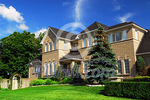 Large upscale residential home with bright green lawn and blue sky Large upscale residential home with bright green lawn and blue sky