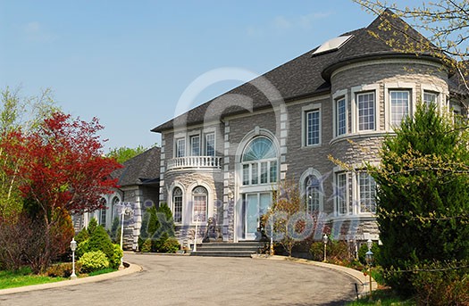Front of a large beautiful executive home under blue sky Front of a large beautiful executive home under blue sky