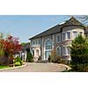 Front of a large beautiful executive home under blue sky