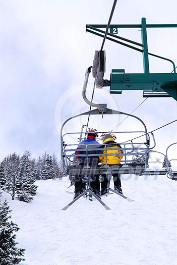 Skiers wearing funny hats on a chairlift in snowy mountains Skiers wearing funny hats on a chairlift in snowy mountains