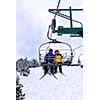 Skiers wearing funny hats on a chairlift in snowy mountains