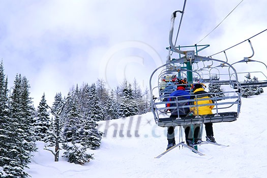 Skiers wearing funny hats on a chairlift in snowy mountains Skiers wearing funny hats on a chairlift in snowy mountains