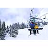 Skiers wearing funny hats on a chairlift in snowy mountains