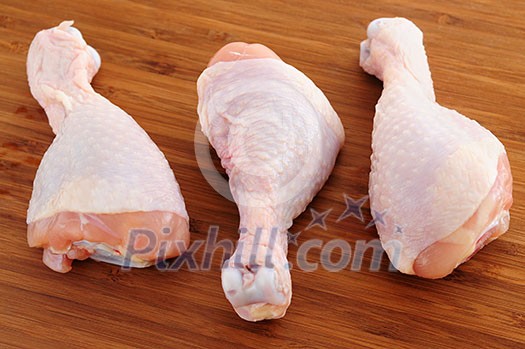 Raw chicken drumsticks on a wooden cutting board Raw chicken drumsticks on a wooden cutting board