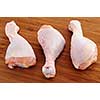 Raw chicken drumsticks on a wooden cutting board