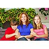 Family of mother and children sitting in front of their house