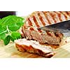 Grilled steak being cut on a cutting board, closeup