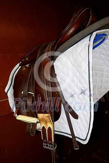Saddle on a rack in a tack room, horseback riding equipment Saddle on a rack in a tack room, horseback riding equipment