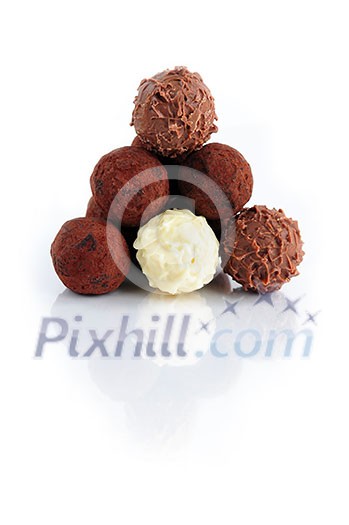 Pyramid of assorted chocolate truffles on white background with reflection Pyramid of assorted chocolate truffles on white background with reflection