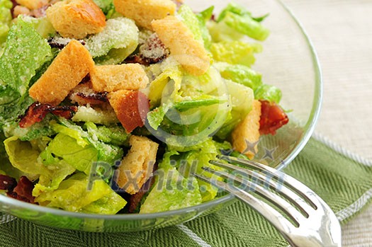 Fresh caesar salad with croutons and bacon bits served in a glass bowl Fresh caesar salad with croutons and bacon bits served in a glass bowl