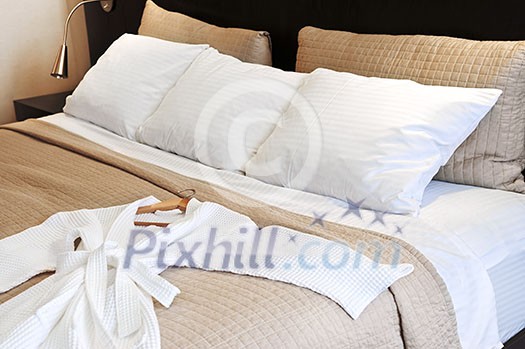 Comfortable bed with clean bathrobe in upscale hotel Comfortable bed with clean bathrobe in upscale hotel