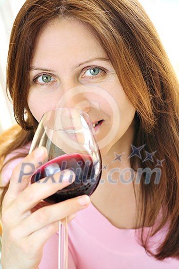 Smiling mature woman holding a glass of red wine Smiling mature woman holding a glass of red wine