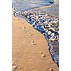 Footprints on sandy tropical beach washed away by waves
