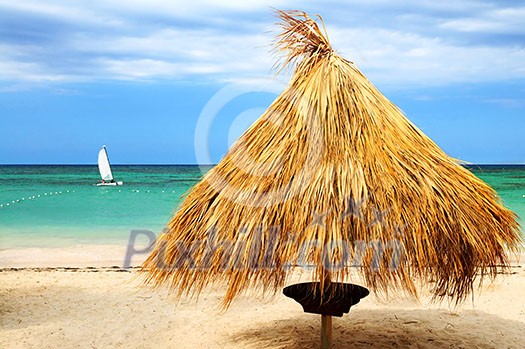 Tropical beach of a Caribbean island with palm branches shelter Tropical beach of a Caribbean island with palm branches shelter