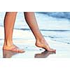 Feet of a young woman touching water on tropical beach