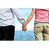 Mature romantic couple holding hands on the beach