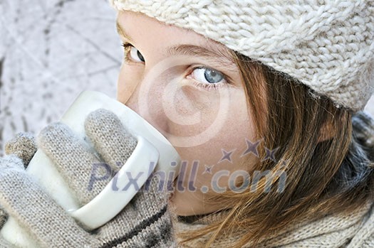 Teenage girl in winter hat with cup of hot chocolate